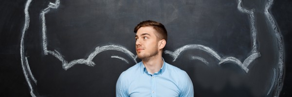 Picture of  funny suited business  man with  fake muscle arms over blackboard. hand whrite. look right