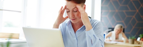 Tired or pensive woman sitting in front of laptop and preparing for report